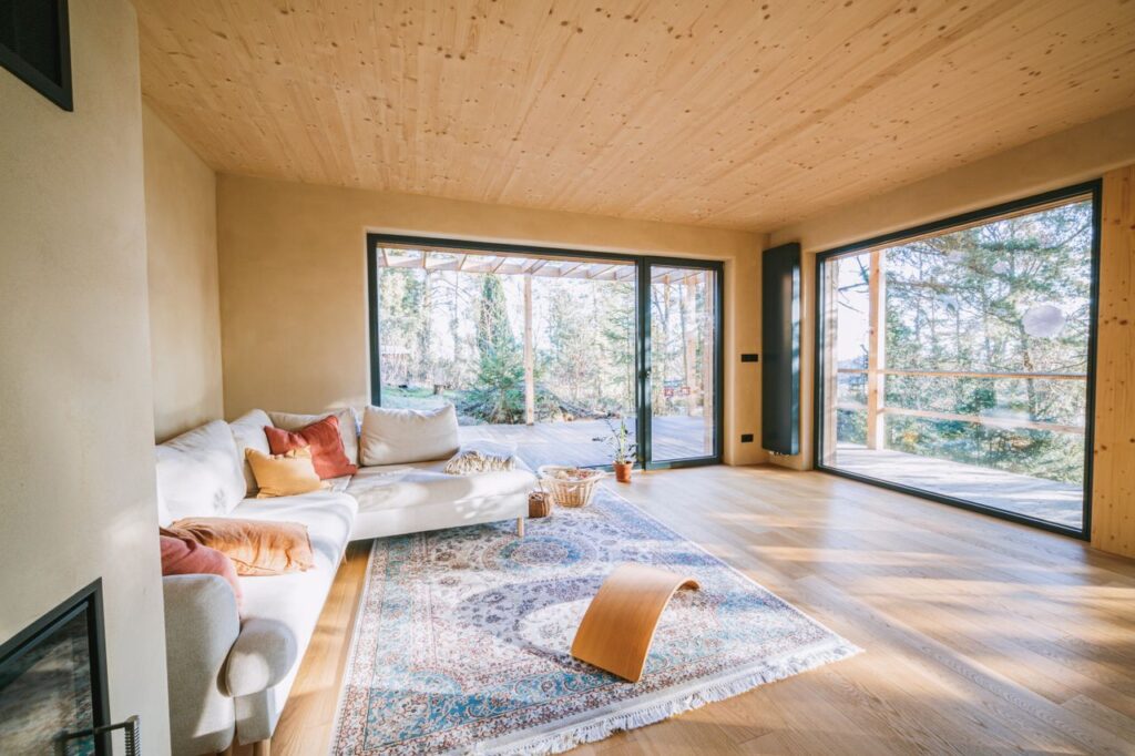 Bright living room with modern design, featuring large windows and cozy furniture.