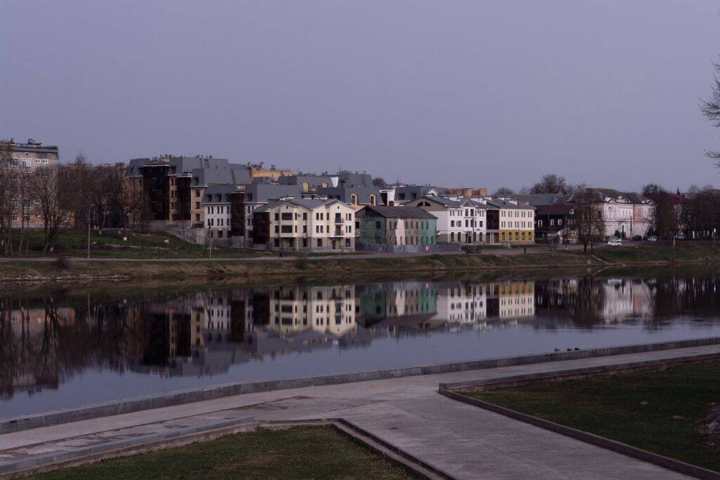 Beautiful riverside homes reflecting in the tranquil water under a soft sky.